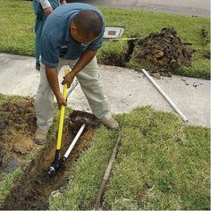 a man is digging in the ground with a yellow shovel and water hose on his head