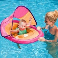 a woman holding a baby in a pool with an inflatable float on it's back