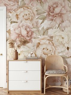 a white dresser sitting next to a wall covered in pink and white flowers on top of a wooden floor