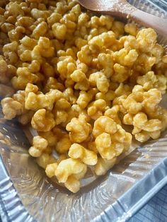 a glass bowl filled with corn kernels next to a wooden spoon