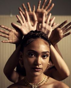 a woman with her hands on top of her head, wearing gold jewelry and bracelets