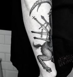 a black and white photo of a person with a tattoo on their arm holding scissors