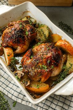 chicken with potatoes and herbs in a white casserole dish on a checkered cloth