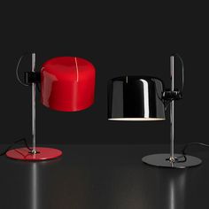 two red and black lamps sitting next to each other on top of a table in front of a black background