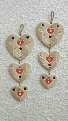 three heart shaped ornaments hanging from strings on a wall with the shape of a cow's head