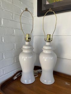 two white lamps sitting on top of a wooden table