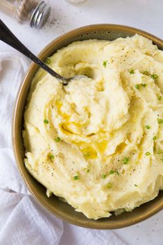 a bowl filled with mashed potatoes on top of a white cloth next to a bottle