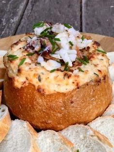 bread with cheese and herbs on it sitting on a plate next to some sliced bread