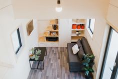 an aerial view of a living room and kitchen area in a tiny home with wood flooring