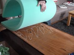 a man is holding a large green object in his hand while standing next to a couch