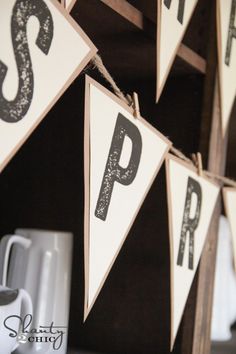 a wooden sign with letters hanging from it's sides on a shelf next to coffee mugs