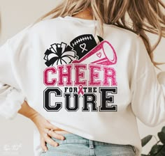 a woman wearing a cheer for the cure sweatshirt with her hands in her pockets and holding a football