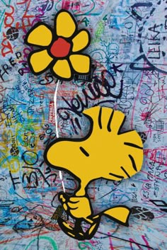 a wall covered in graffiti with a cartoon character holding a flower