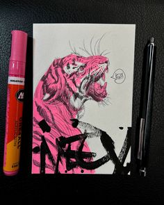 a drawing of a pink tiger on a piece of paper next to a marker and pen