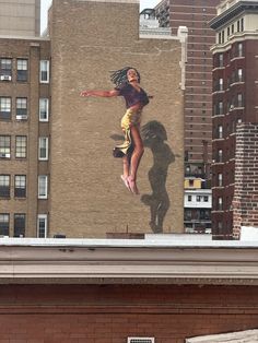 a woman is jumping in the air on top of a building with buildings behind her