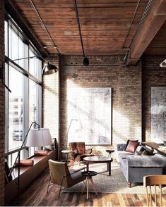 a living room filled with lots of furniture next to large windows on the wall and wooden flooring