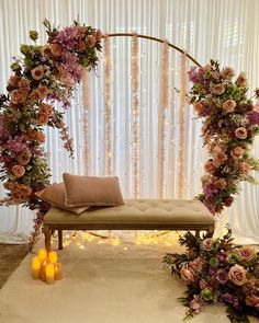 a bench with flowers and candles in front of a curtained backdrop for a wedding ceremony