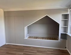 an empty room with some shelves and a bed in the corner, all painted white