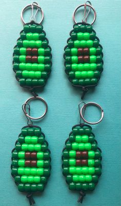 three pieces of green and brown bead with metal hooks on a blue table top