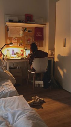 a person sitting at a desk in a bedroom