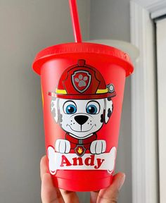 a person holding up a red cup with a fireman dog on it and a straw