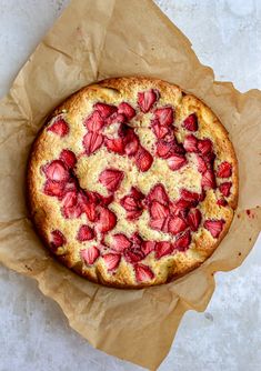 a cake with strawberries on it sitting on wax paper