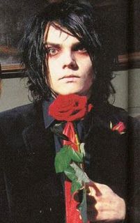 a man with long hair wearing a suit and tie holding a rose in his hand