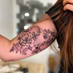 a woman's arm with flowers and an elephant tattoo on her left arm, while she is combing her hair