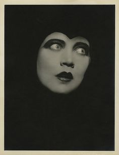 an old photo of a woman with black makeup on her face and eyes, looking into the distance