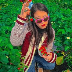 a young woman wearing sunglasses and holding strawberries in her hands