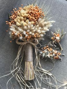 dried flowers are arranged on a gray cloth with twine wrapped around the stems and roots