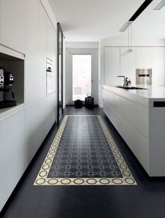 a black and white kitchen with an ornate rug on the floor in front of it