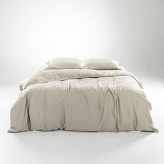 an unmade bed with white sheets and pillows