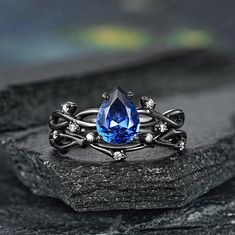 a ring with a blue stone surrounded by white diamonds on top of a black rock