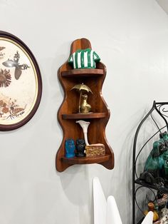 a wooden shelf with various items on it next to a wall clock and other decorations