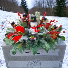 a christmas arrangement in a grave with snow and evergreens on the ground next to it