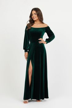 a woman wearing a green velvet dress with long sleeves and thigh high slits, posing for