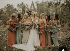 a group of women standing next to each other in front of trees and leaves on the ground