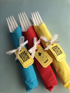 four forks are wrapped in colorful paper and tied with white ribbon on each fork holder