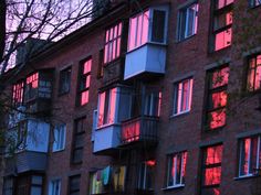 an apartment building with many windows and balconies lit up at sunset or dawn