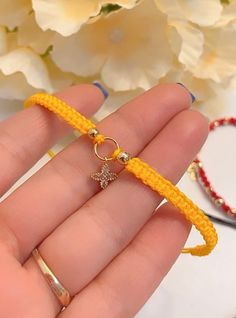 a hand holding a yellow bracelet with a cross on it