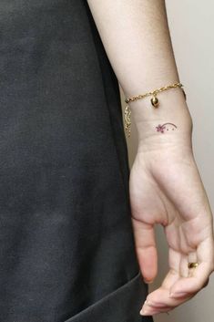 a person with a small tattoo on their left hand and a gold chain around the wrist