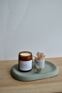 a candle sitting on top of a wooden table next to a cup filled with matches