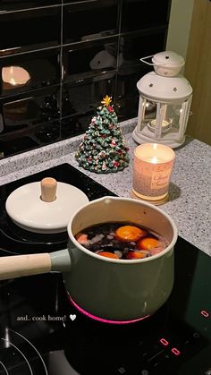 a pot filled with liquid sitting on top of a stove next to a lit candle