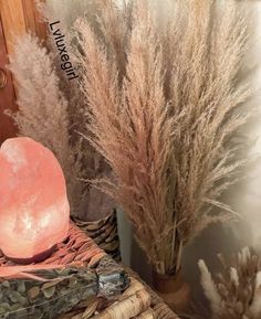 some dried plants are sitting on a wicker basket next to a vase with a rock in it