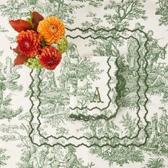 an arrangement of flowers is placed on a green and white toiler tablecloth