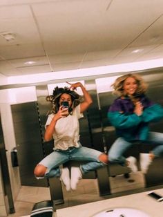 two women are jumping in the air with their cell phones and one is taking a selfie