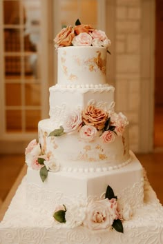 a three tiered wedding cake with flowers on the top and sides, sitting on a table