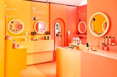 an orange and yellow store with round mirrors on the wall, shelves filled with cosmetics