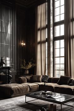 a living room filled with lots of furniture next to large windows covered in sheer curtains